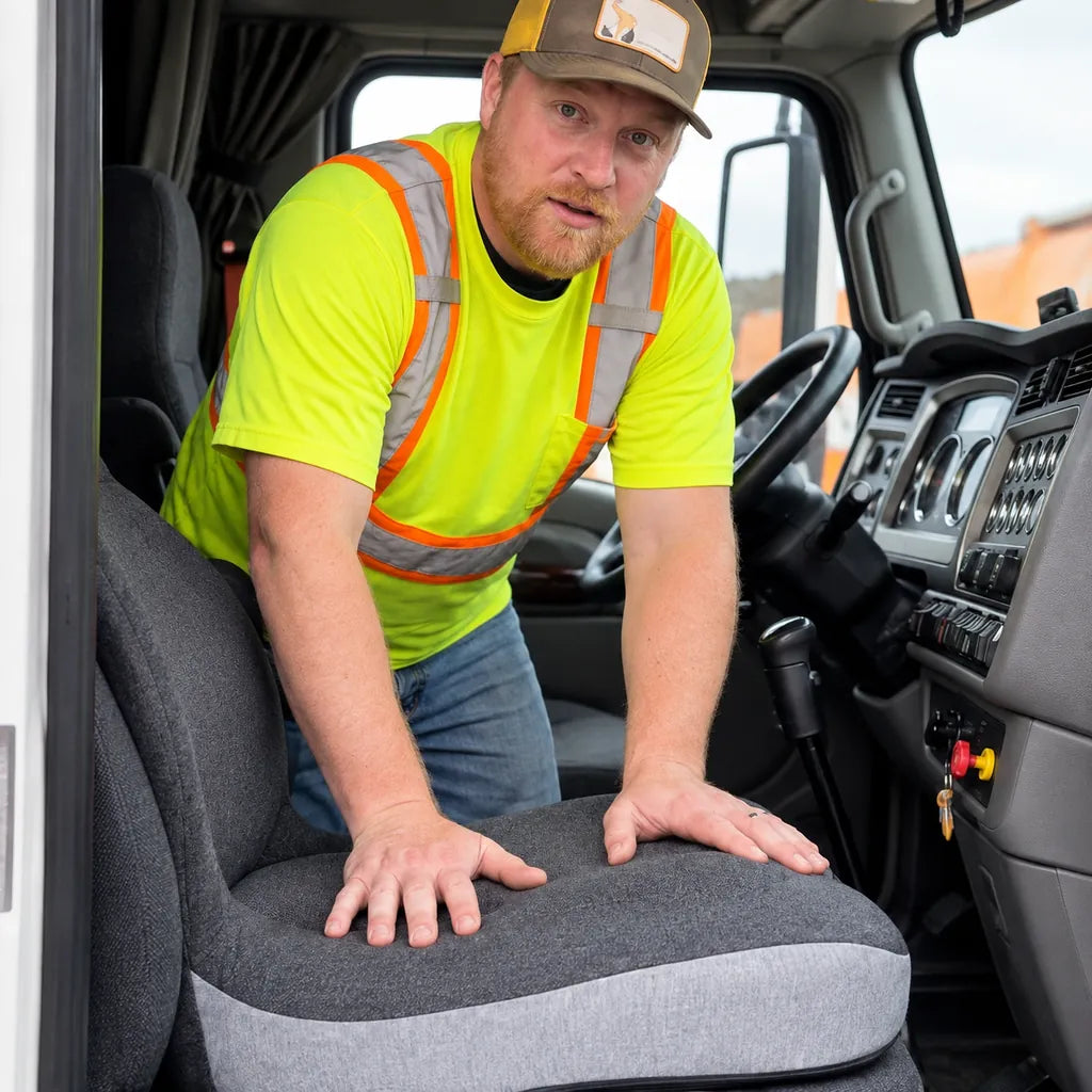 Illustrative hands pressing the CELINVA cushion on a truck seat, preserving the supplied interaction.